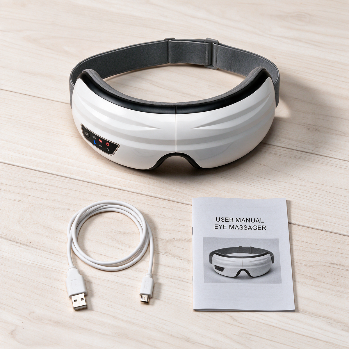 The Nove Body Heated Eye Massager laid out beside its micro-USB charging cable and user manual